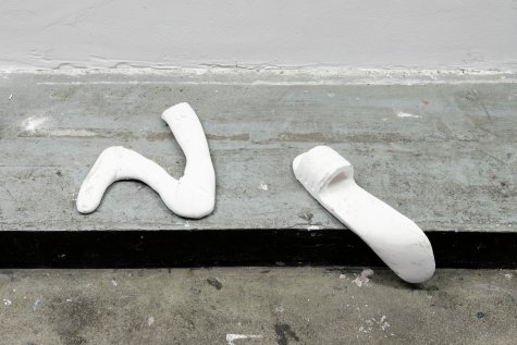 Installation view of the work tschüss in the parking lot of the Kunsthalle. Various sculptures are mounted on the wall.