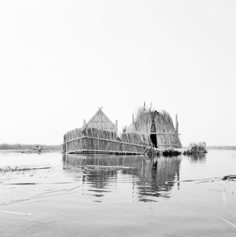 Das Schwarzweißfoto zeigt zwei aus Bambus gefertigte Zelte, die auf einem See scheinbar wie durch ein Wunder schweben.
