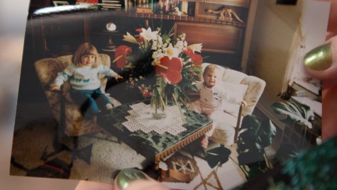 A photo held in one hand. It shows two small children behind a huge bouquet of flowers.